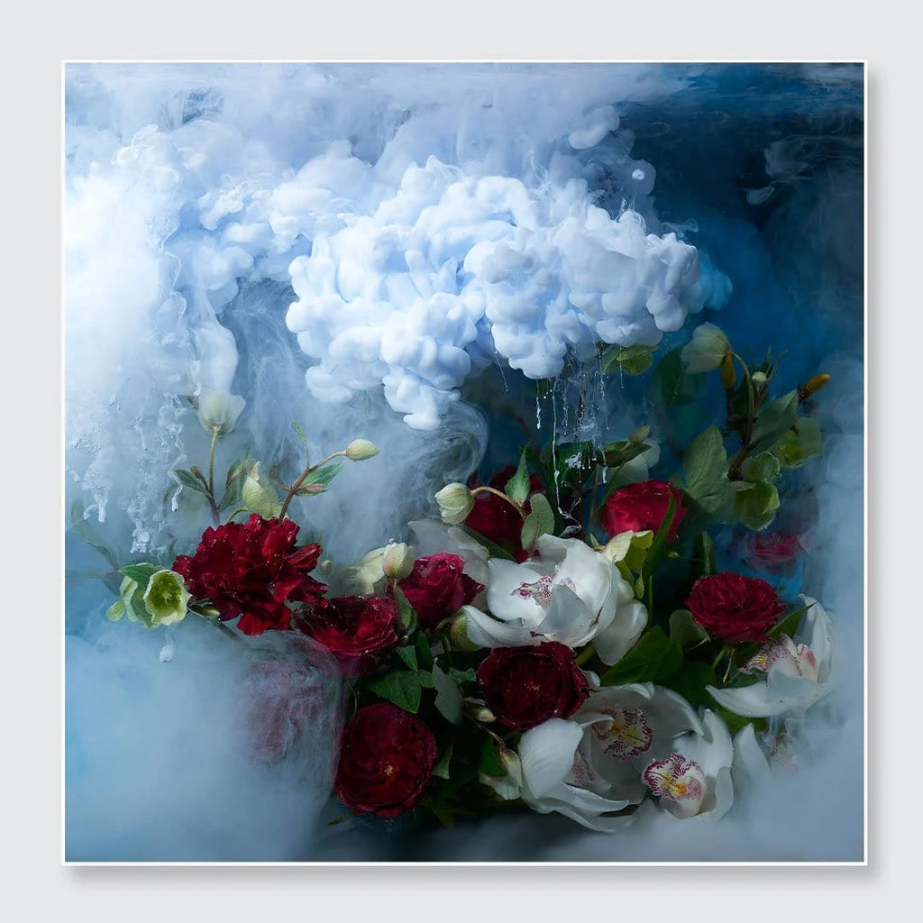 A square floral art print featuring a bouquet of red and white flowers, including roses and orchids, emerging from swirling white smoke against a deep blue background.