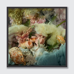 A framed square art print featuring a soft, dreamy floral and shell composition in pastel tones, including cream, pink, peach, pale yellow, and light blue, set against a light gray background.