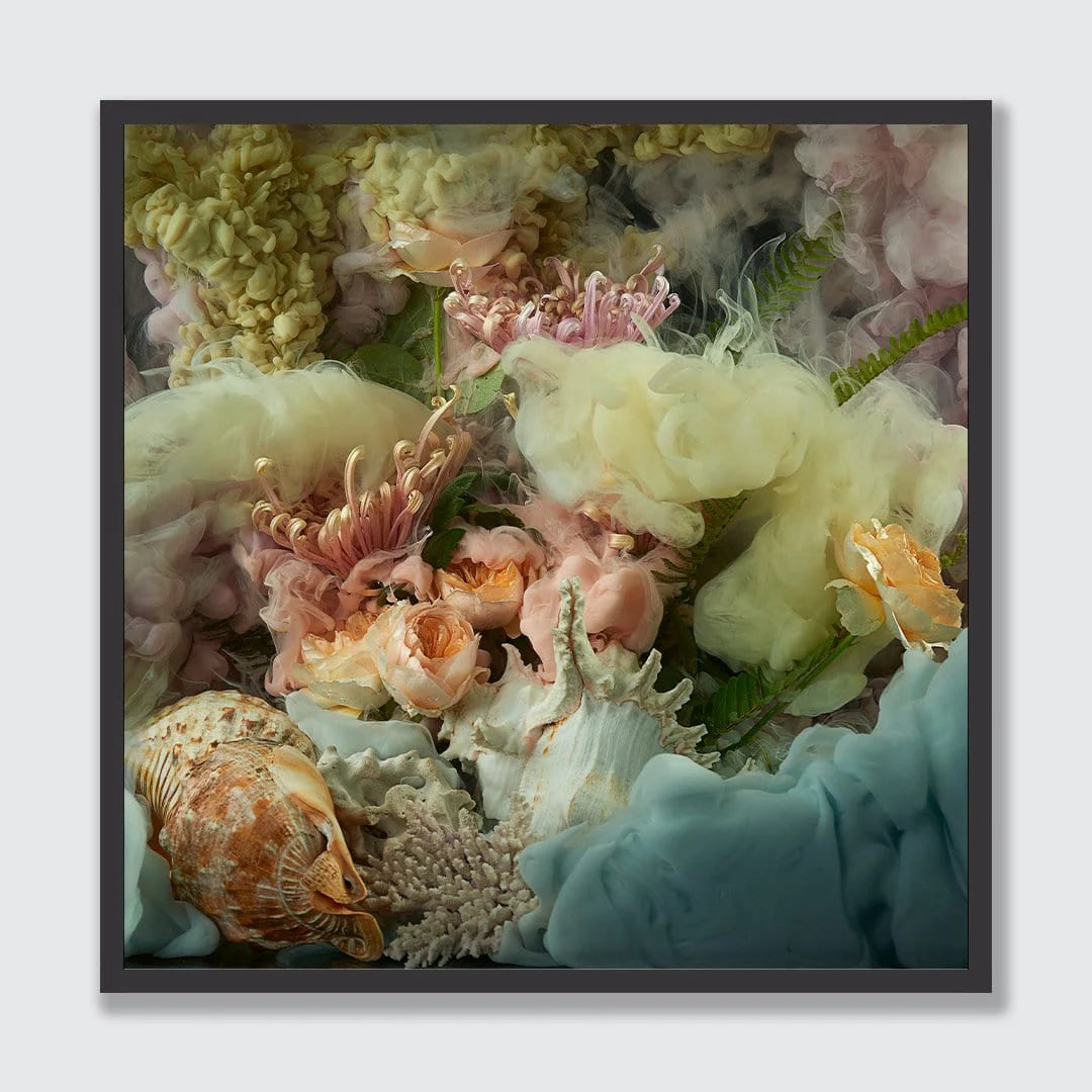 A framed square art print featuring a soft, dreamy floral and shell composition in pastel tones, including cream, pink, peach, pale yellow, and light blue, set against a light gray background.