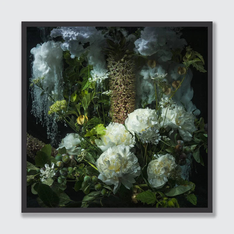 A framed floral art print featuring white peonies, green foliage, and textured white cloud-like forms against a dark background, presented in a thin black frame on a light gray wall.